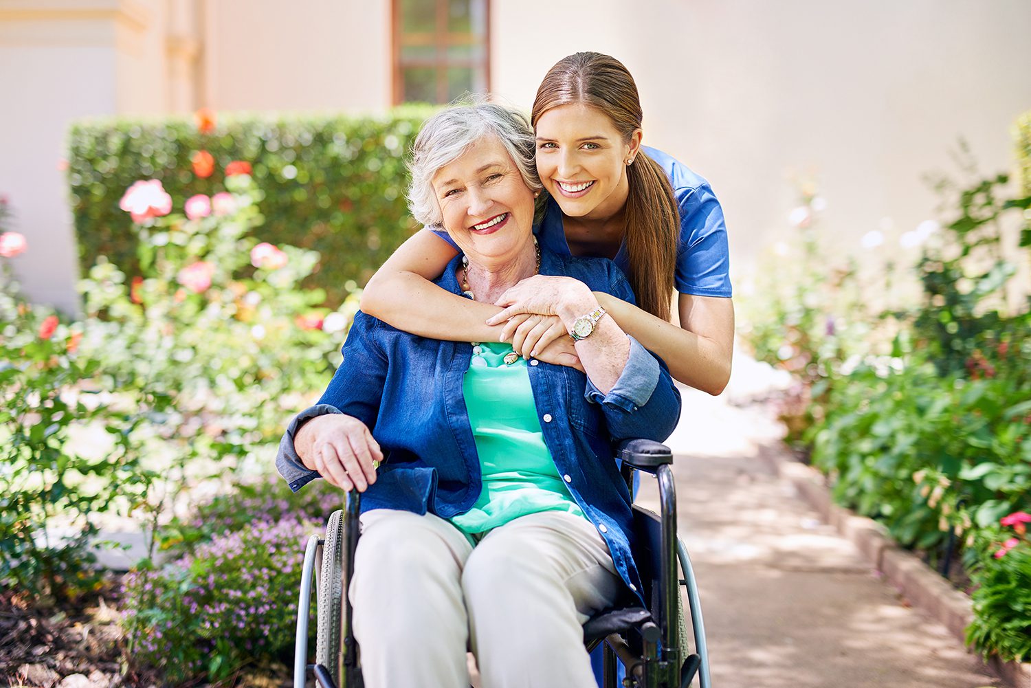a healthcare worker with her arms around a woman sitting on a bench, both are smiling